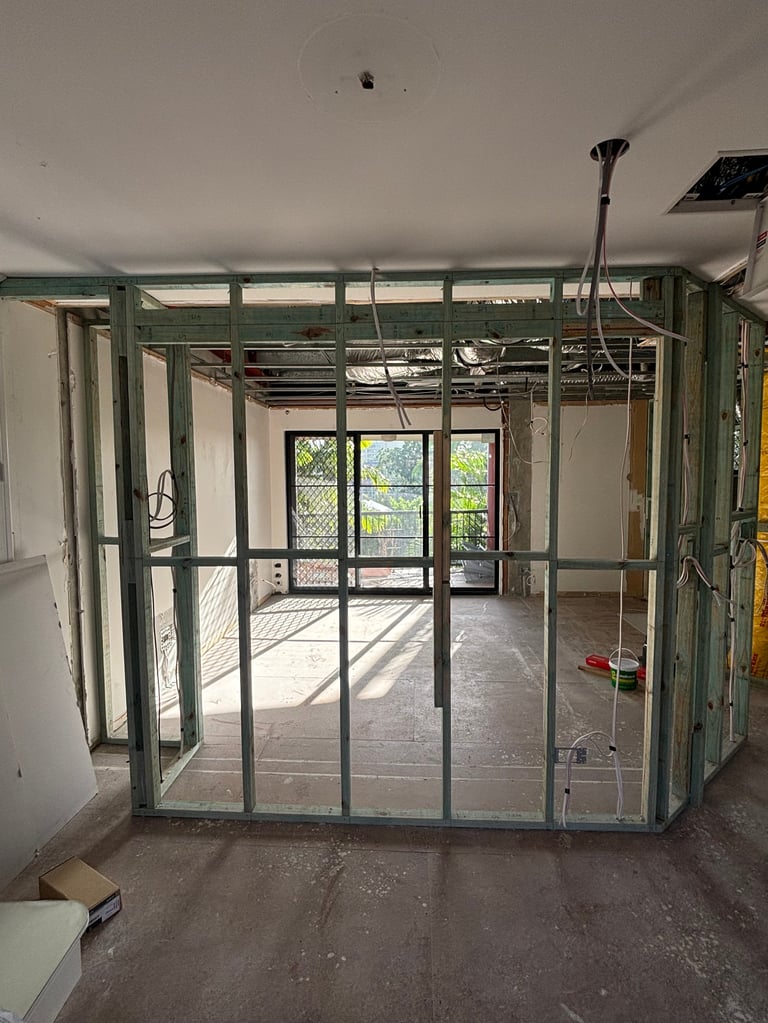 Interior construction framing with metal studs and glass doors leading to outdoor patio area