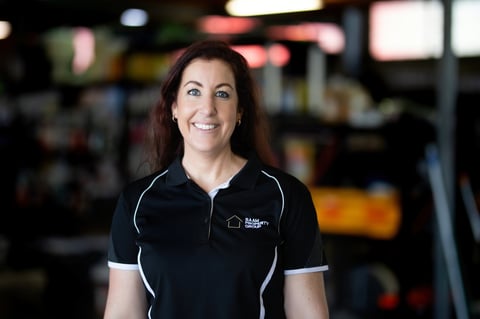 Professional woman in black polo shirt with white trim smiling at camera in modern office setting